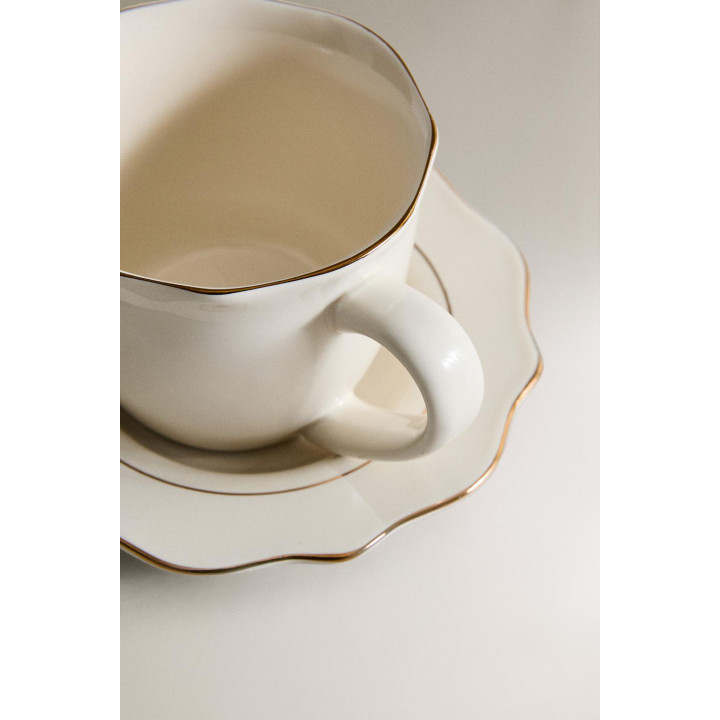 Фарфоровая чашка и блюдце с деталями на краю